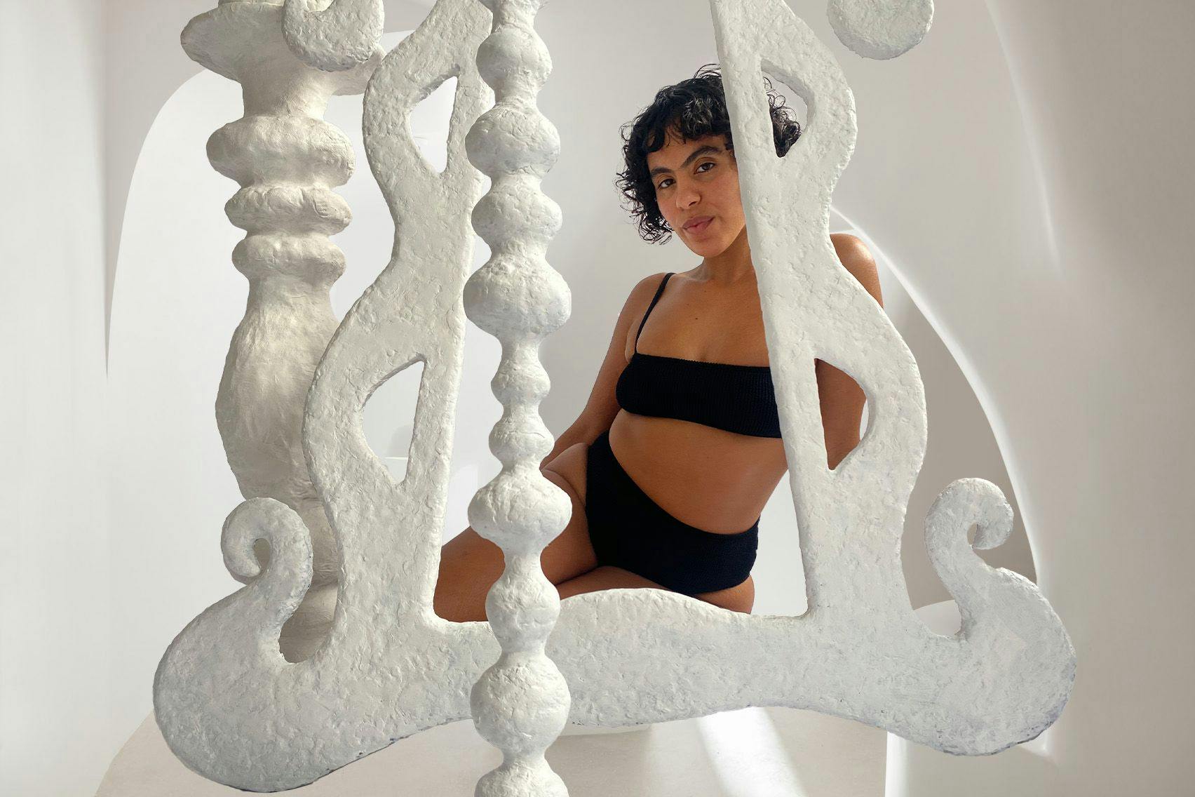 Nadine in black bikini behind sculptures