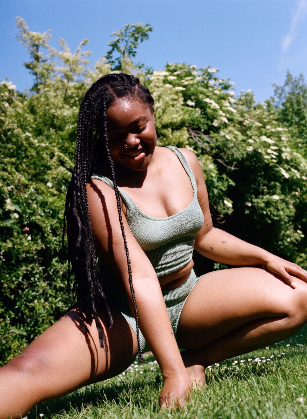 Esther on grass in green swimsuit top and shorts 